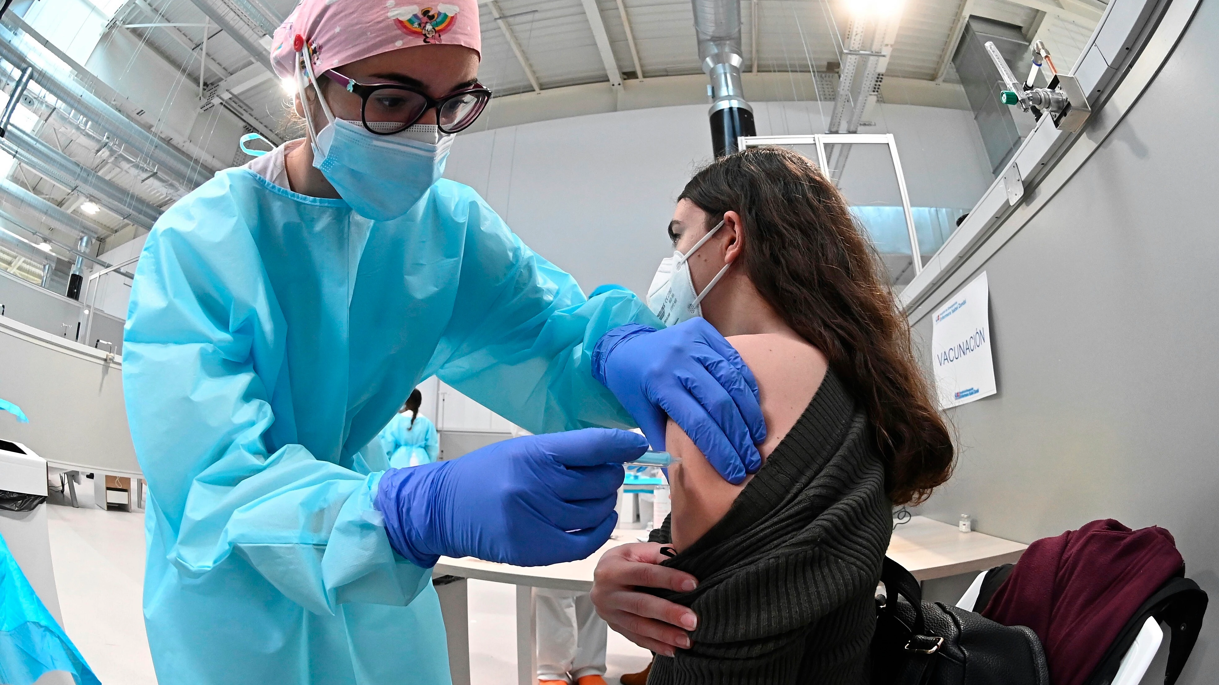 Una sanitaria pone la vacuna contra la covid-19 a una mujer en el hospital Isabel Zendal.