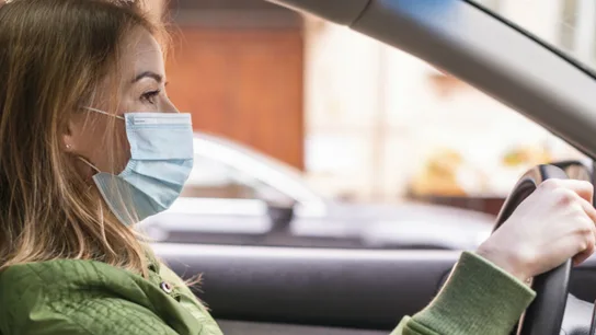 Una mujer conduce con la mascarilla puesta Una mujer conduce con la mascarilla puesta