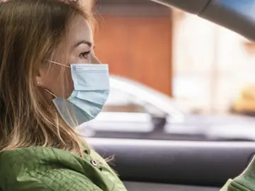 Una mujer conduce con la mascarilla puesta Una mujer conduce con la mascarilla puesta
