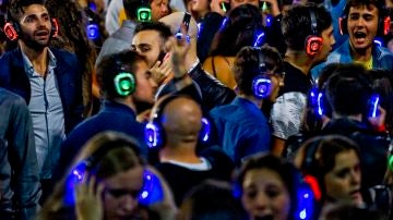 Centenares de jóvenes bailan al ritmo de la música, a través de auriculares, en la plaza Municipio de Nápoles, Italia, durante la celebración de una "Fiesta Silenciosa"