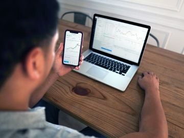 Un hombre realiza unas gestiones con su ordenador y su teléfono móvil