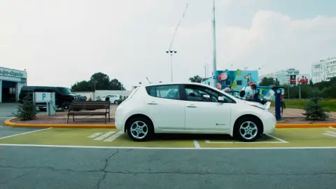 Un coche eléctrico en un área de servicio Un coche eléctrico en un área de servicio
