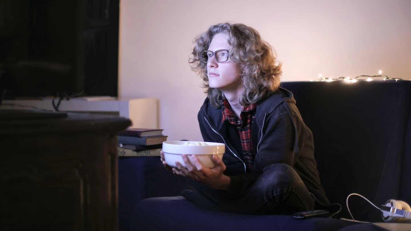 ¿Sufres 'doomscrolling'? Esta es la nueva adicción que nos ha creado la pandemia Una chica está sentada en el sofá viendo la televisión y comiendo palomitas