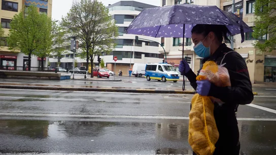 Una mujer se protege de la lluvia con un paraguas mientras camina con una bolsa de patatas durante el Martes Santo Tiempo Semana Santa