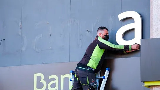 Un operario retira las letras de Bankia  Un operario retira las letras de Bankia