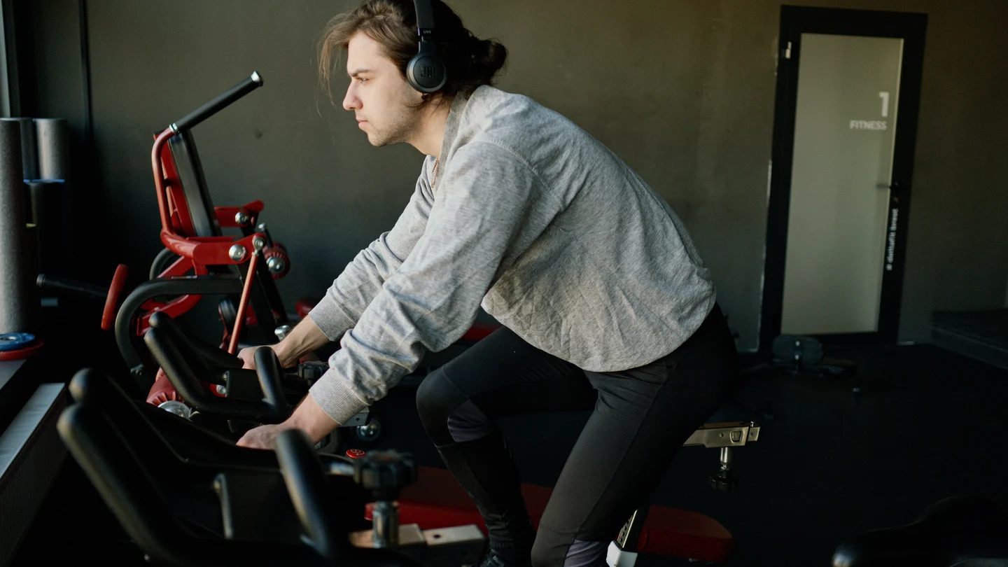 Un hombre hace deporte sobre una bicicleta estática mientras escucha música Un hombre hace deporte sobre una bicicleta estática mientras escucha música