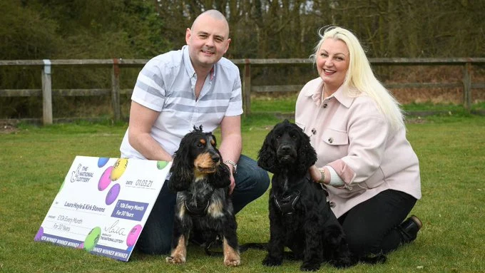 La pareja afortunada posa junto a sus perros y el cheque del premio