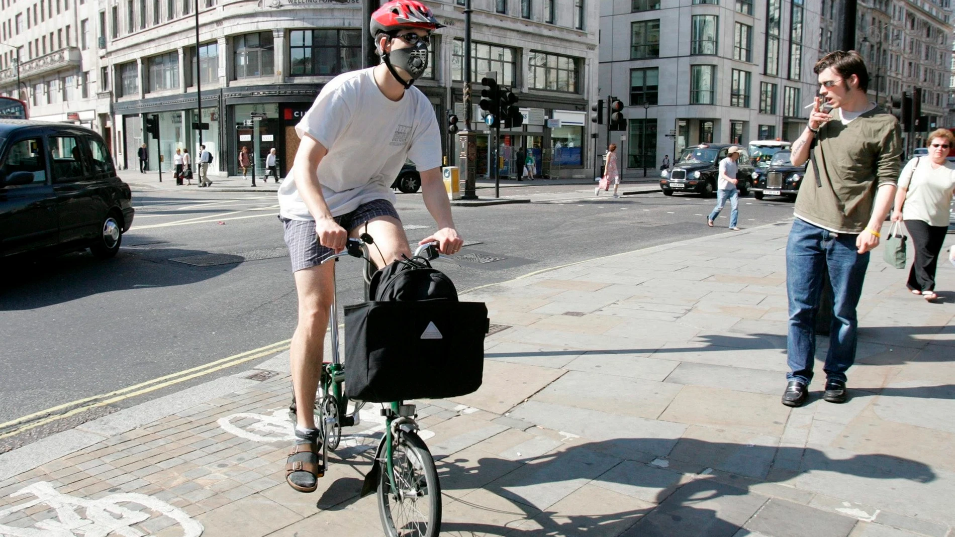 Un londinense se dirige a trabajar en bicicleta con mascarilla en la cara en Londres, Reino Unido.