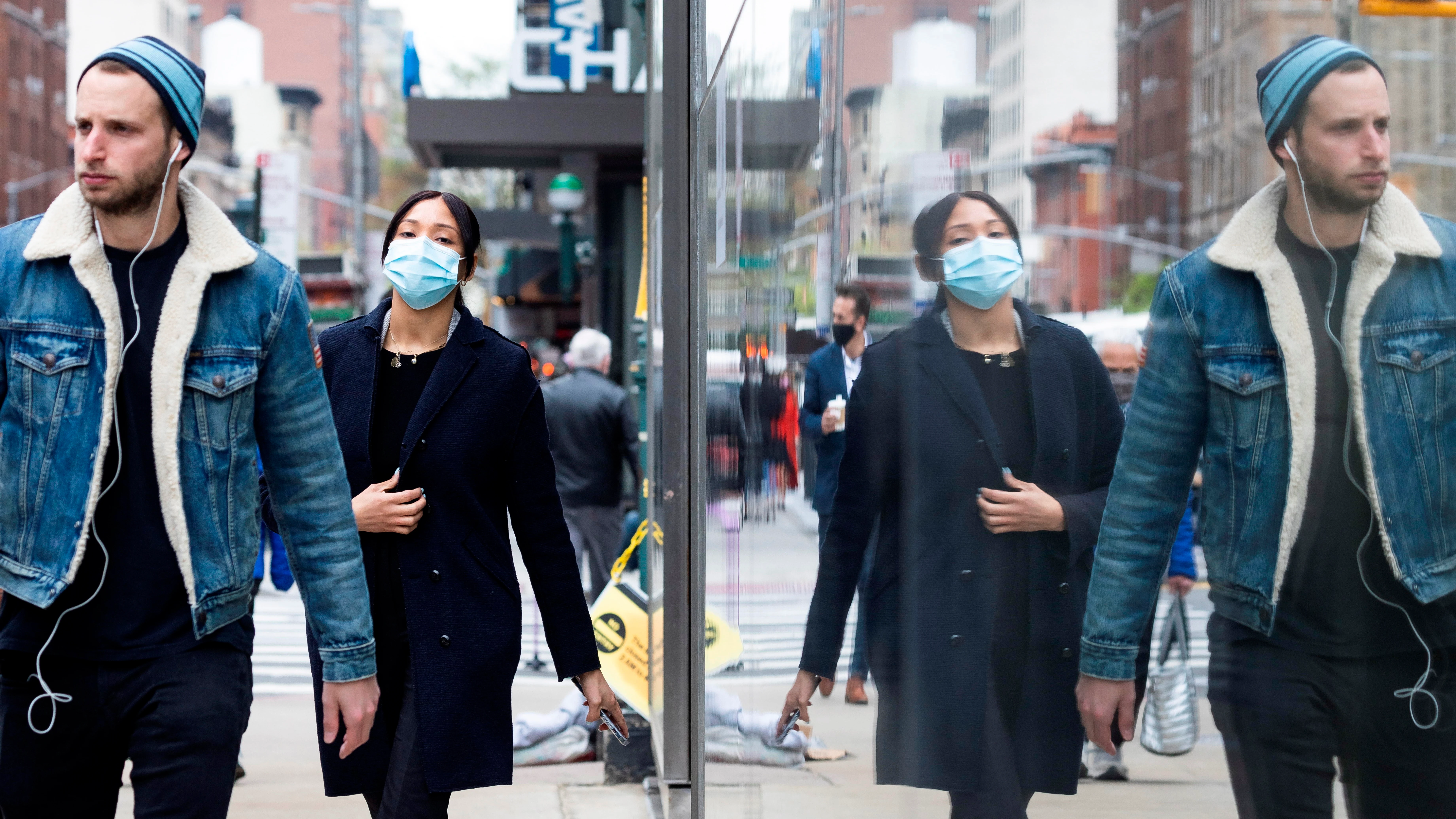 Personas con y sin mascarilla caminan por una calle de Nueva York