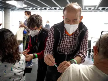 Dos personas reciben sus respectivas dosis de vacuna en el Wizink Center de Madrid.