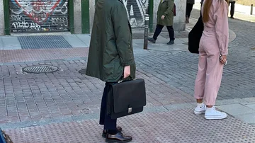 Una mujer espera en la cola para votar con un maletín en la mano