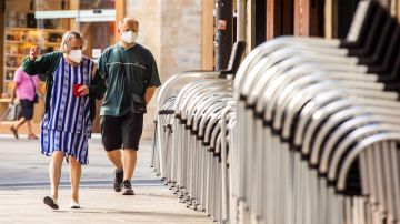 Dos personas con mascarilla por la calle