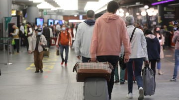 Varias personas caminan con su equipaje por la estación de Madrid - Puerta de Atocha, a 14 de mayo de 2021, en Madrid 