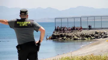 Un agente de la Guardia Civil observa desde lejos la llegada de inmigrantes