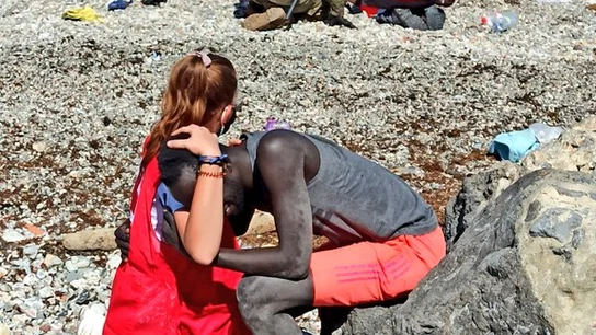 Una mujer de Cruz Roja abraza a un migrante que acaba de llegar a suelo Español Una mujer de Cruz Roja abraza a un migrante que acaba de llegar a suelo Español
