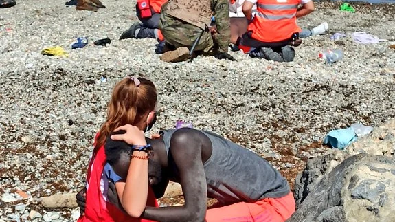 Una mujer de Cruz Roja abraza a un migrante que acaba de llegar a suelo Español