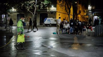 Un hombre riega una calle de Barcelona, una semana después del fin del estado de alarma, en Barcelona