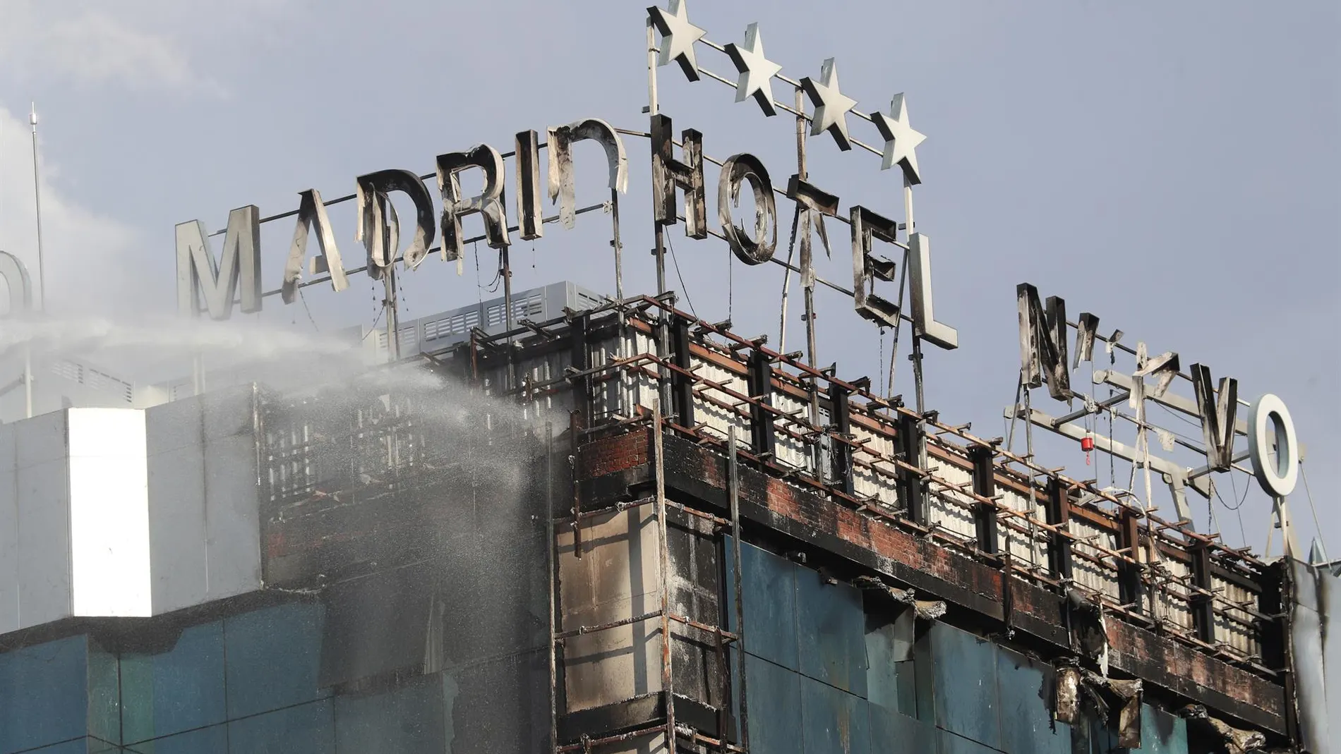  Bomberos extinguen las llamas tras un aparatoso incendio en la fachada exterior del Hotel Nuevo Madrid.