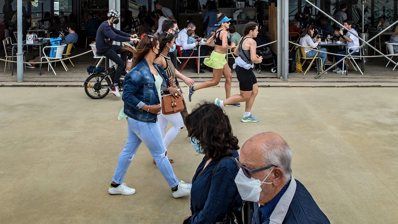 Varias personas pasean frente a un chiringuito del Paseo Marítimo de la Barceloneta