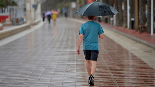 Un hombre camina este sábado bajo la lluvia Un hombre camina este sábado bajo la lluvia