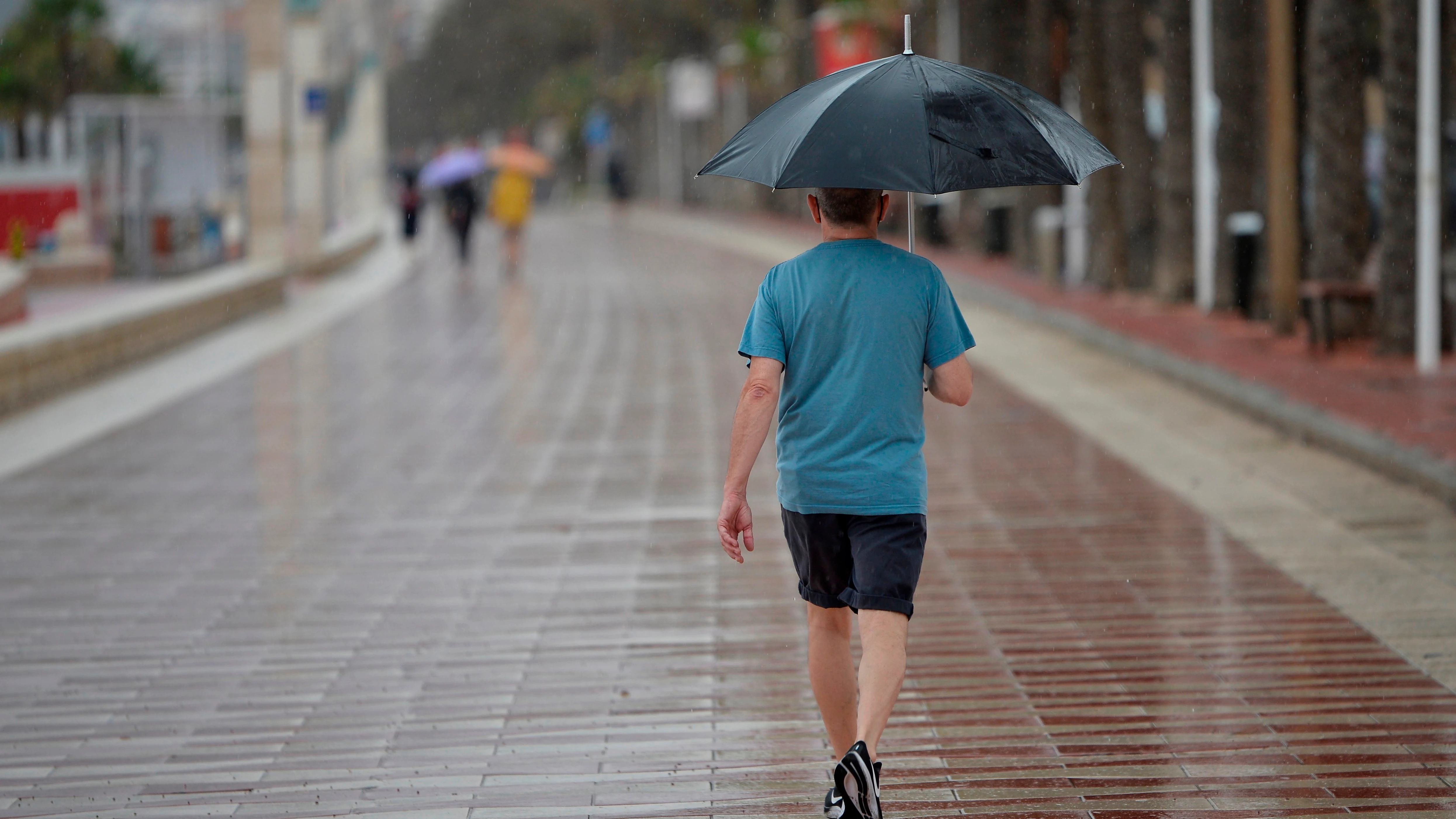 Un hombre camina este sábado bajo la lluvia