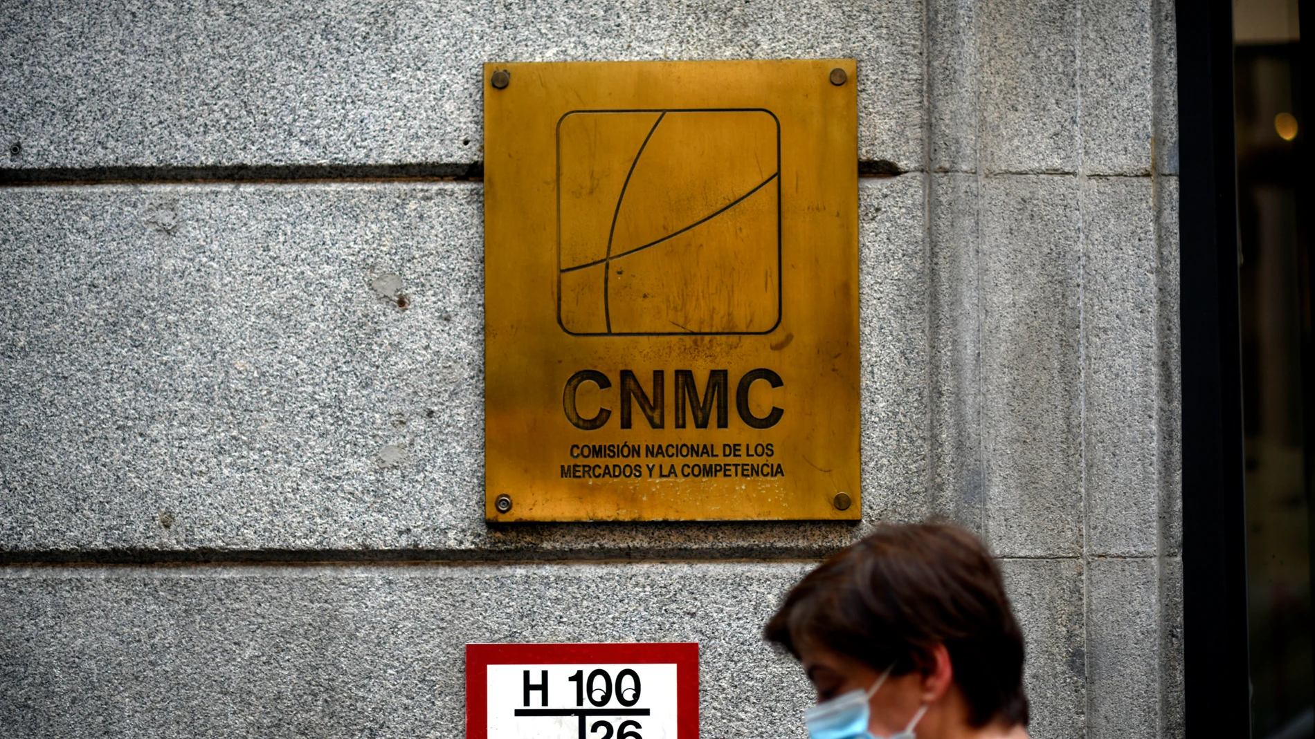 Una mujer pasa por el edificio de la CNMC, en Madrid