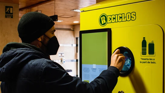 Un hombre echa una botella de refresco en una máquina de RECICLOS Un hombre echa una botella de refresco en una máquina de RECICLOS