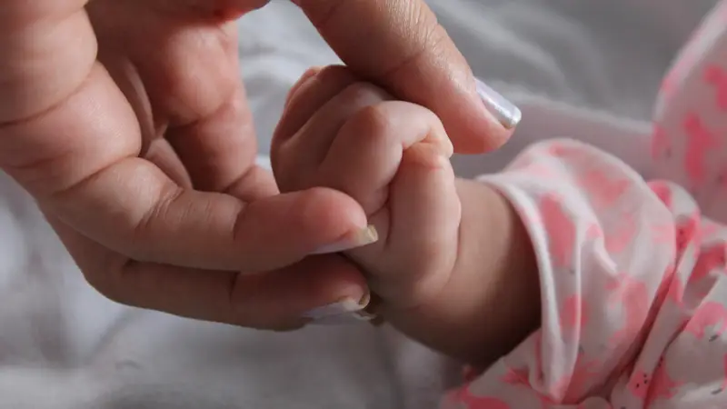 Imagen de archivo de una madre sujetando la mano de su bebé.
