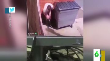 Un hombre haciendo sus necesidades tras un contenedor
