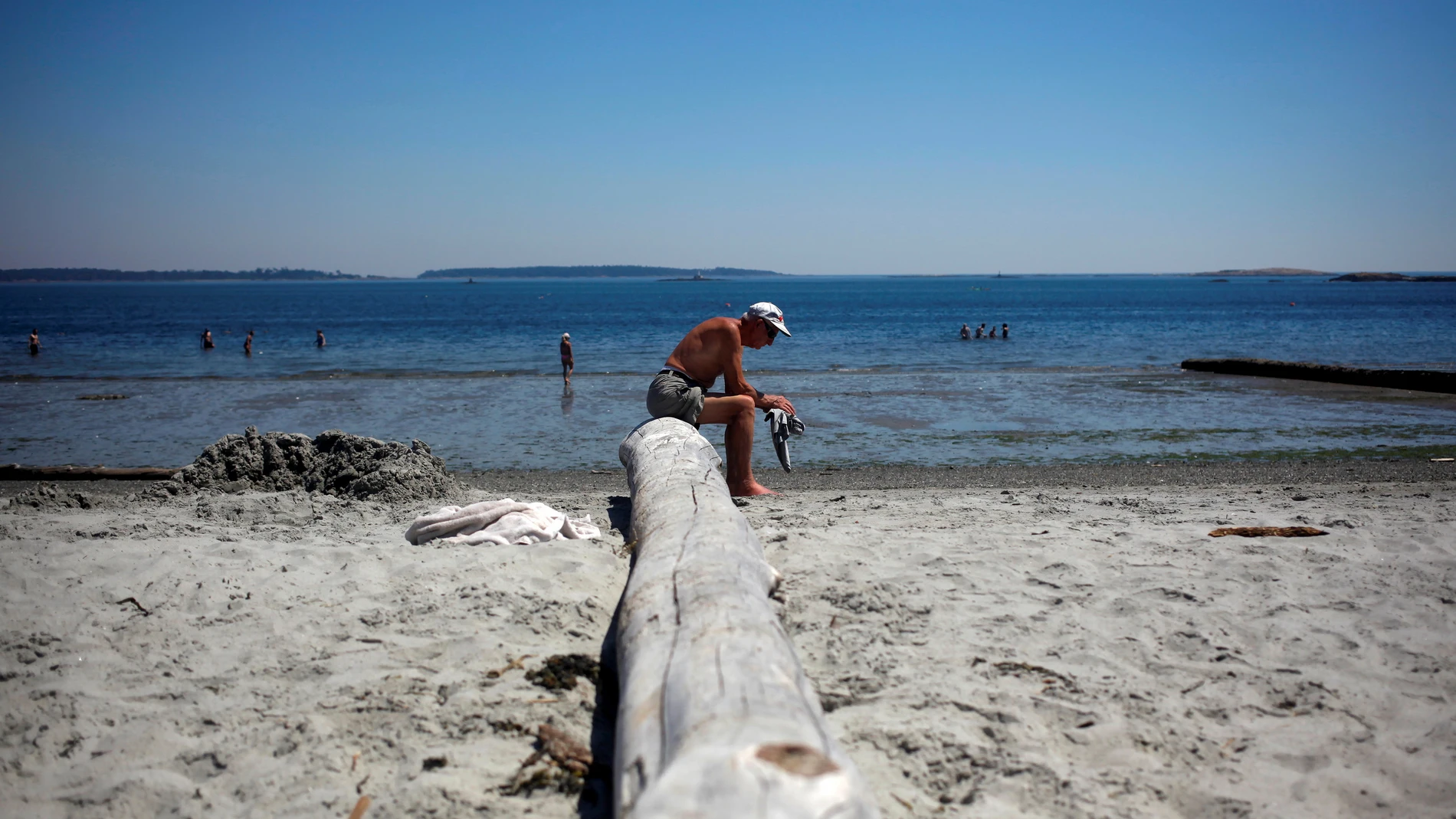 Un hombre descansa en Willow&#39;s Beach durante la &quot;cúpula de calor&quot; que se cierne actualmente sobre la Columbia Británica y Alberta