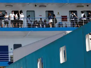  Varias personas saludan desde el ferry en el que viajan 118 estudiantes que habían sido confinados en un hotel de Mallorca tras el macrobrote.