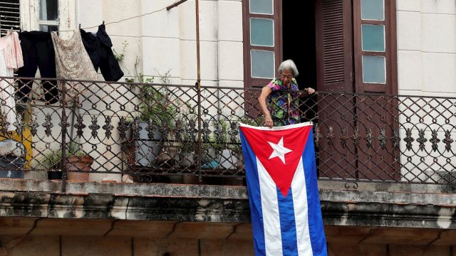 Una mujer sale al balcón donde se expone una bandera cubana