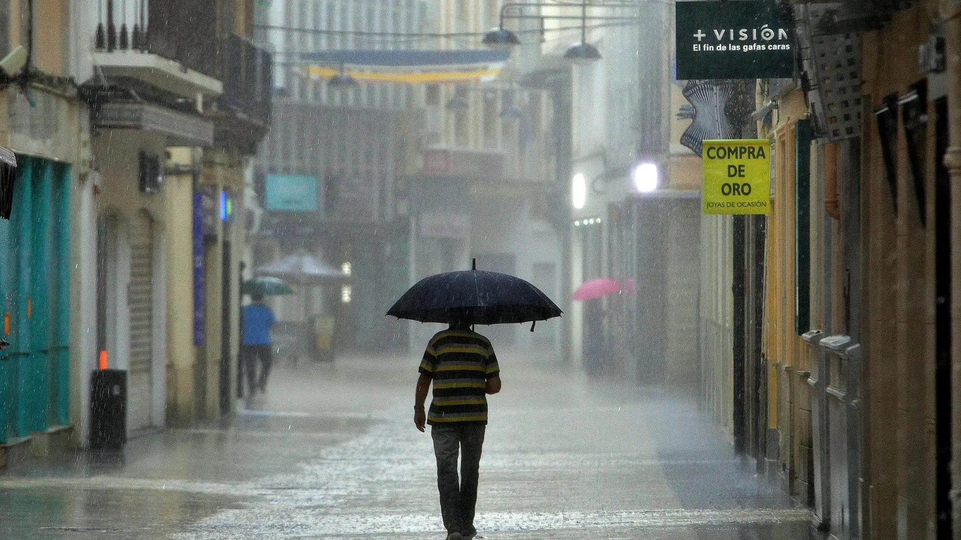 Un hombre camina bajo una intensa lluvia por el centro de la ciudad de Gandía