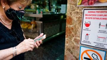 Una mujer busca en su móvil su certificado Covid momentos antes de acceder al interior de una cafetería de Santa Cruz de Tenerife
