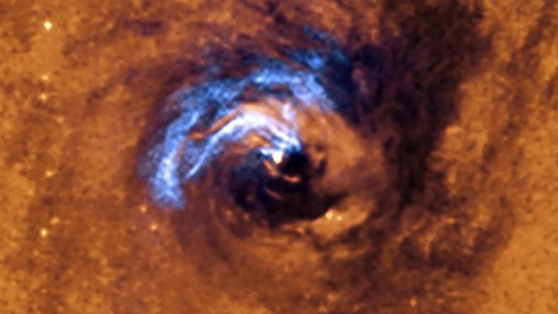 Imagen que muestra la alimentación nuclear de un agujero negro, y cómo los filamentos de polvo que envuelven el núcleo quedan atrapados y giran en espiral 