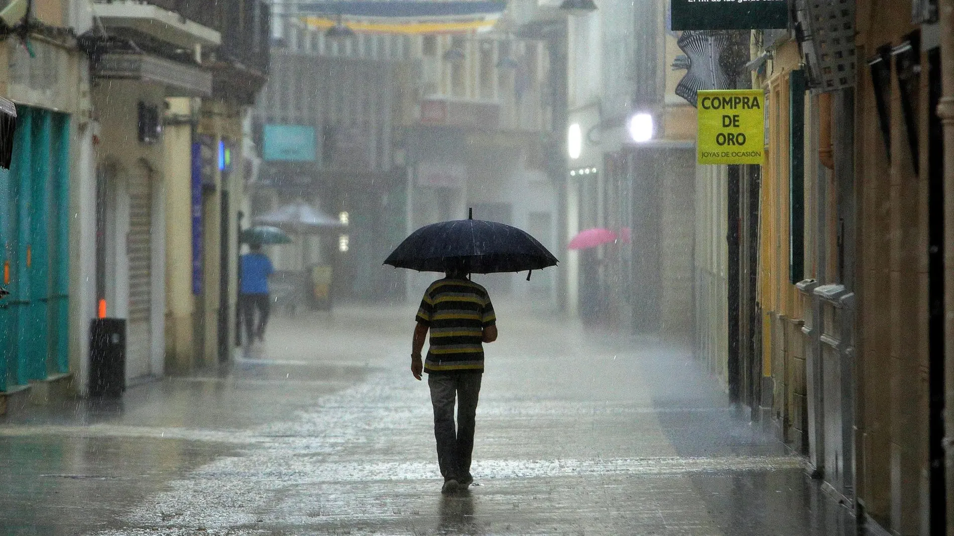 Un hombre camina bajo una intensa lluvia por el centro de la ciudad de Gandía, Valencia