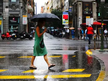 Una mujer se protege de la lluvia en el centro de Madrid