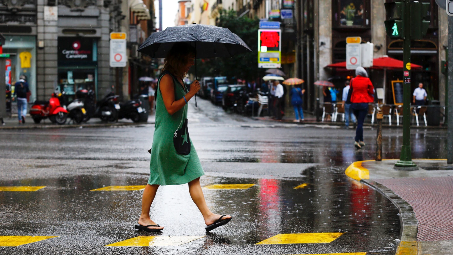 Una mujer se protege de la lluvia en el centro de Madrid