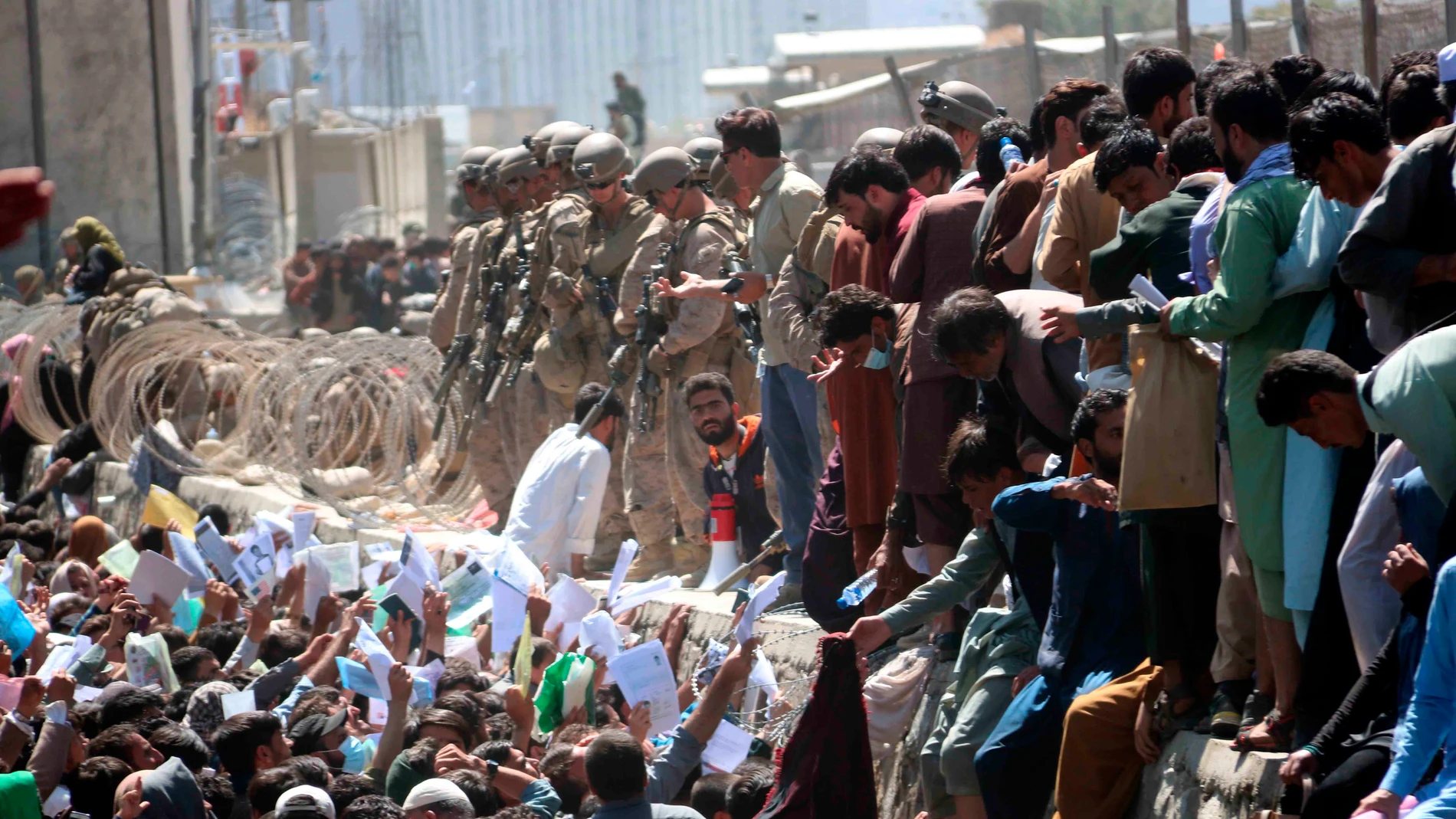 Afganos muestran credenciales mientras intentan contactar con las fuerzas internacionales para intentar huir del país