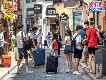 Un grupo de turistas esperan junto a sus maletas en el centro histórico de Valencia.