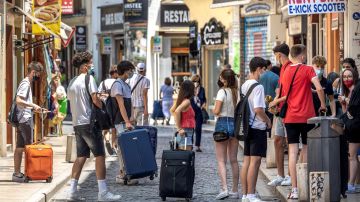 Un grupo de turistas esperan junto a sus maletas en el centro histórico de Valencia.