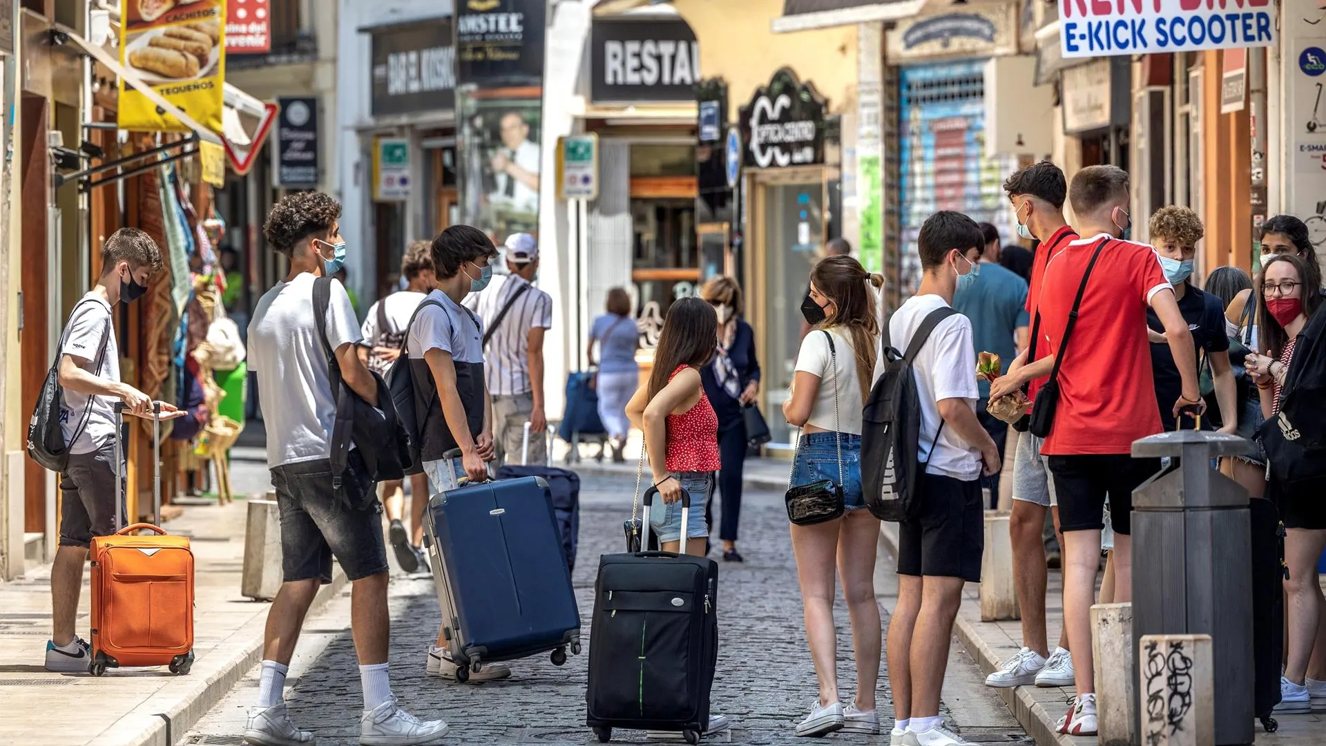 Un grupo de turistas esperan junto a sus maletas en el centro histórico de Valencia.