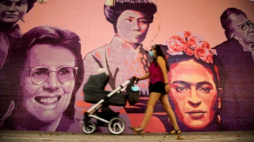 Una mujer camina junto al mural de las mujeres del barrio de Ciudad Lineal en Madrid