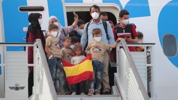 Una familia de evacuados afganos llega a la base de Torrejón con una bandera de España.