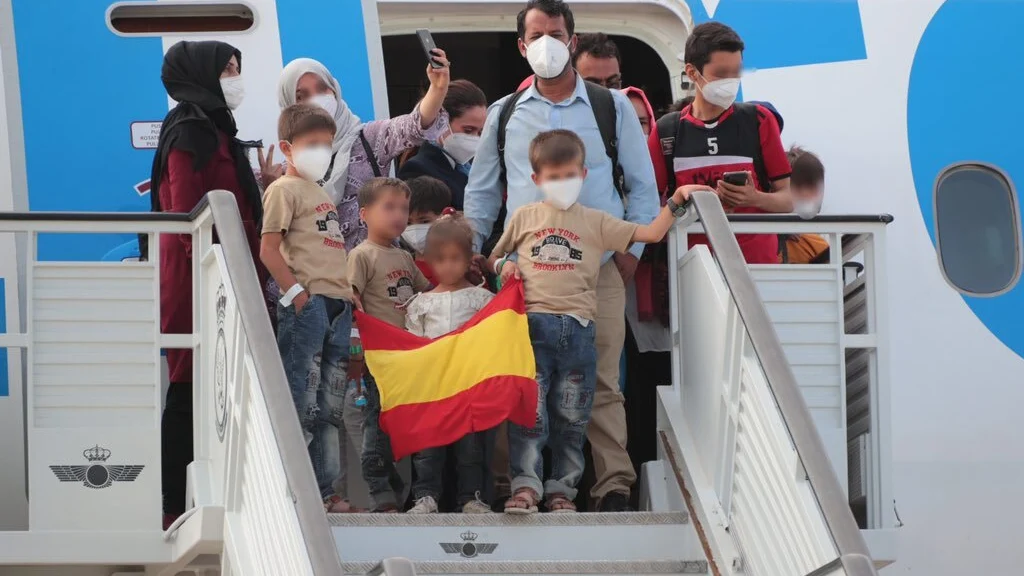 Una familia de evacuados afganos llega a la base de Torrejón con una bandera de España.