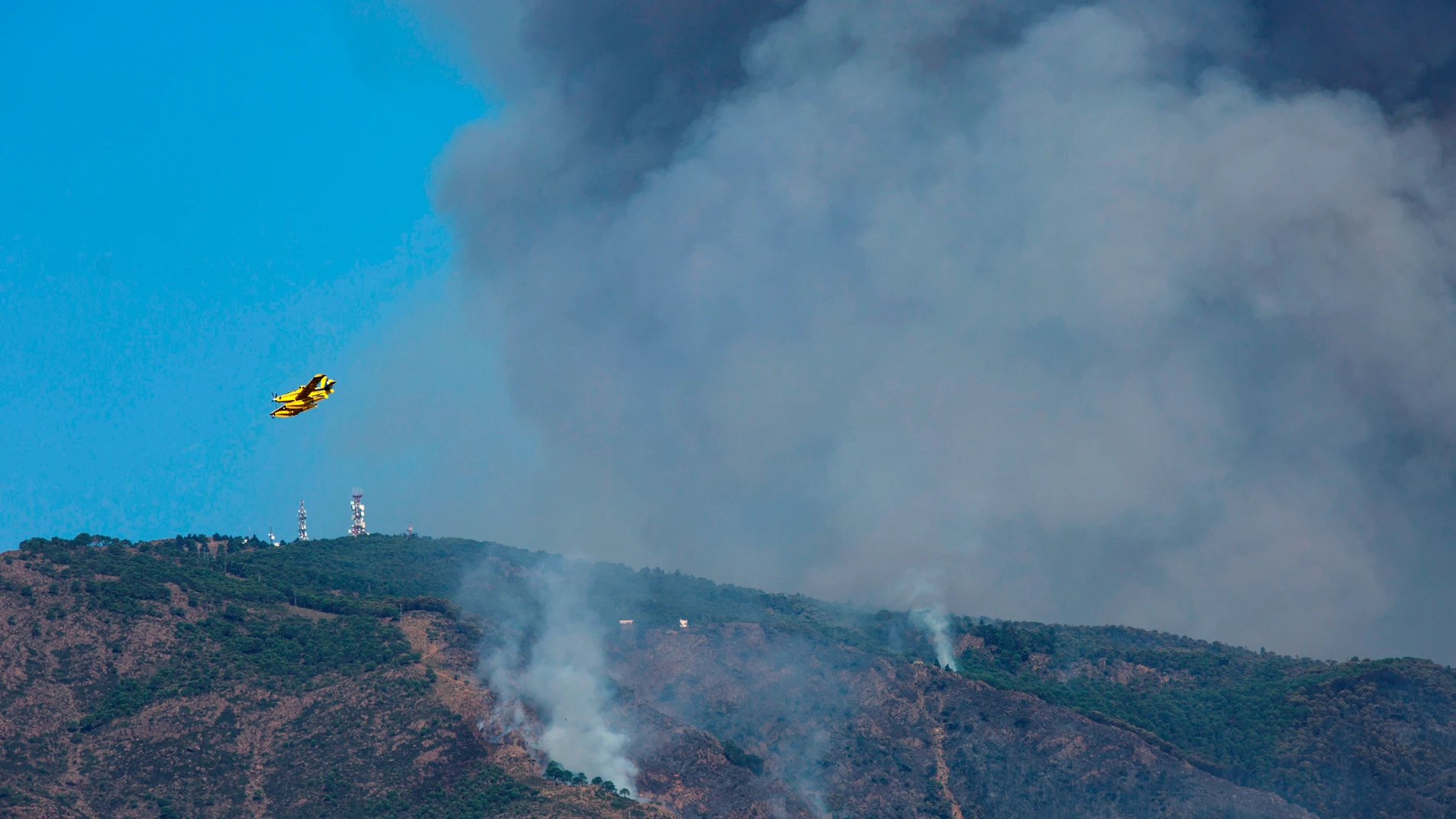 Un hidroavión sobrevuela la zona quemada por el fuego del incendio de Sierra Bermeja