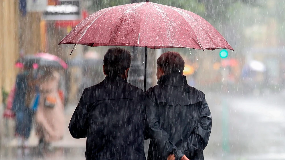 Imagen de dos personas protegiéndose de la lluvia con un paraguas