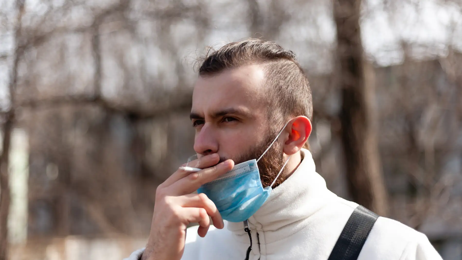 hombre fumando en la calle con mascarilla