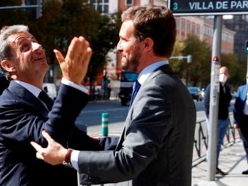 l líder del PP, Pablo Casado (dcha), saluda al expresidente francés Nicolás Sarkozy