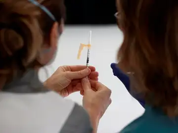 Dos enfermeras observan una dosis de la vacuna, en foto de archivo